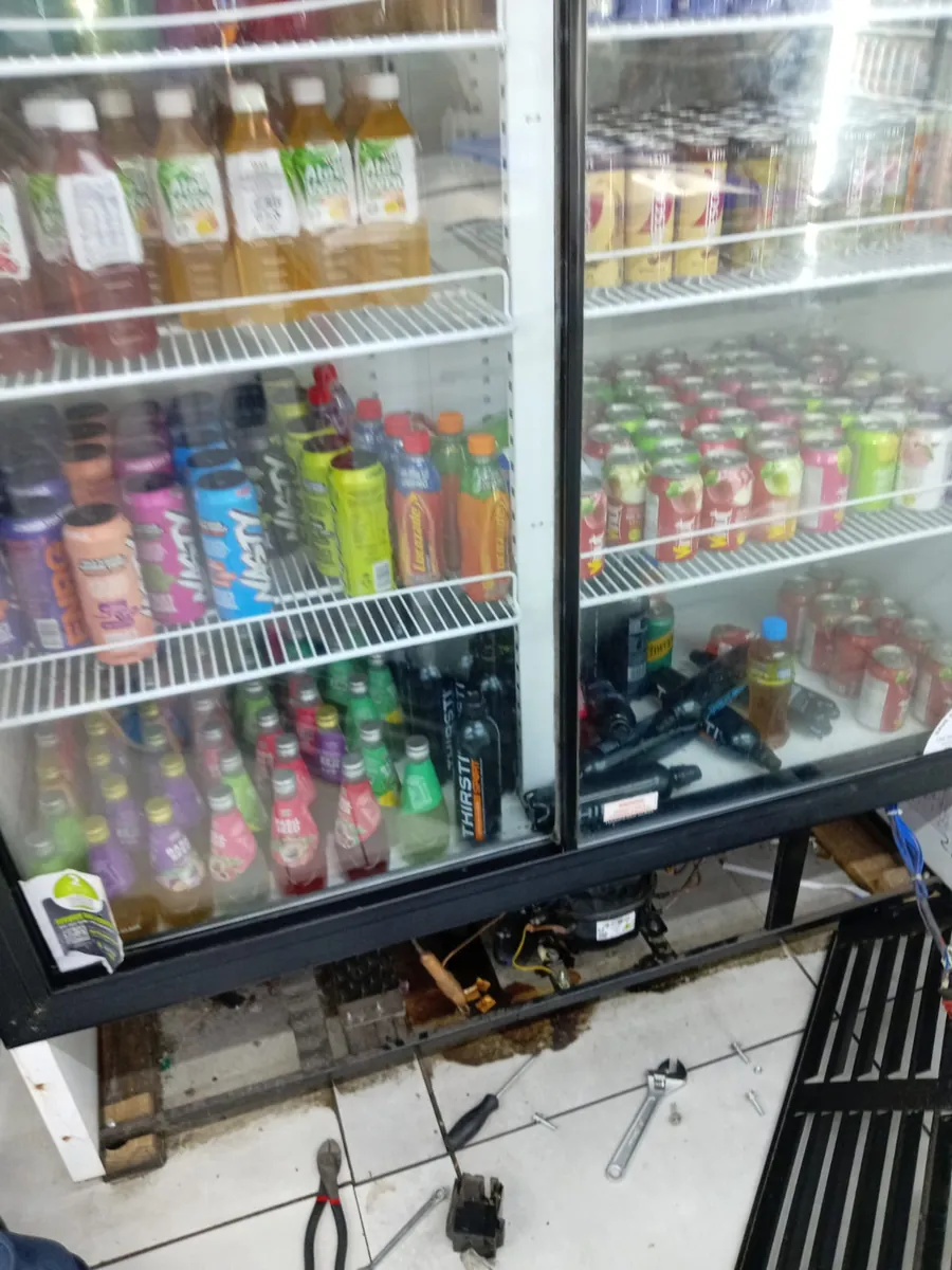 Bottle cooler with the base panel removed and tools laid out for a repair