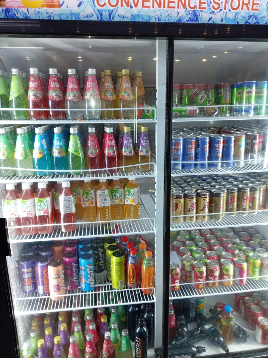 Glass-door bottle coolers fully stocked with drinks in a convenience store